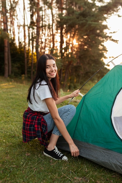 Free photo portrait of young woman fixing tent