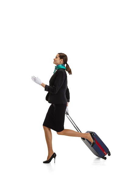 Free photo portrait of young woman, flight attendant running with suitcase isolated on white background