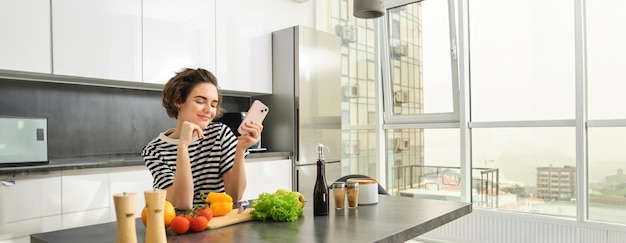 Free photo portrait of young woman food blogger posting on social media recipe vegan salad standing in the