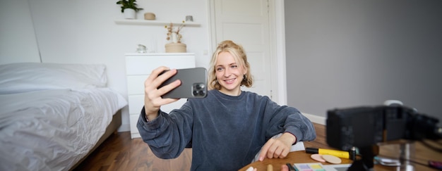 Free Photo portrait of young woman girl beauty blogger recording vlog in her bedroom doing makeup tutorial for