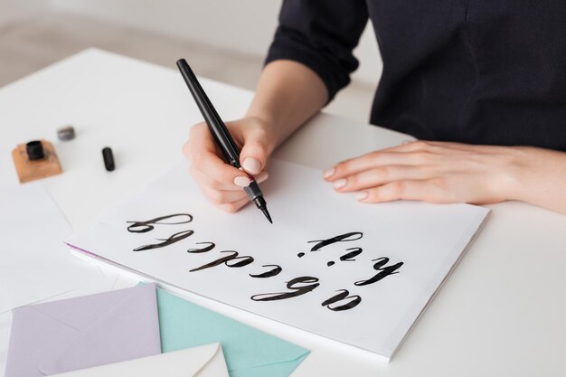 Portrait of young woman hands writing alphabet on paper on desk isolated