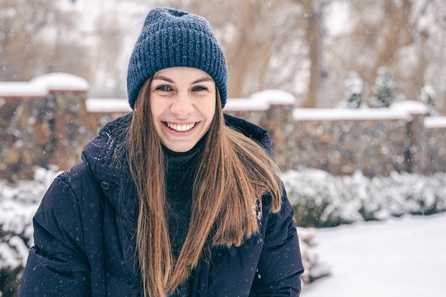 Portrait of a young woman in a hat and a down jacket in winter