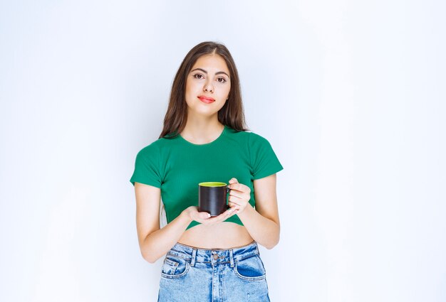 Portrait of young woman holding cup of tea on white background.