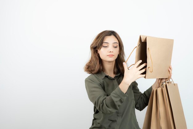 Portrait of young woman holding paper craft bags and standing. High quality photo