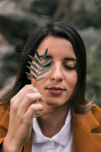 Portrait of a young woman holding twig in front of her eyes