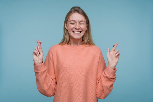 Free Photo portrait of a young woman keeping her fingers crossed