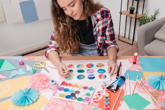 Portrait of young woman painting abstract circle on white paper