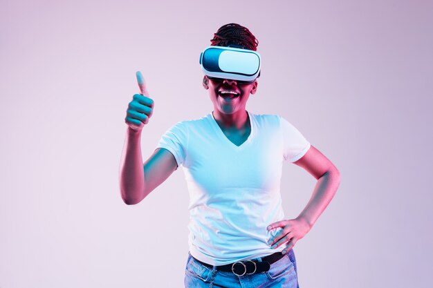 Portrait of young woman playing in VR-glasses in neon light