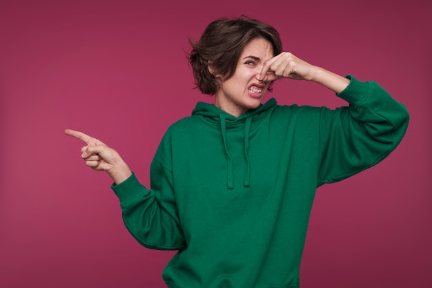 Free photo portrait of a young woman pointing at something that smells bad