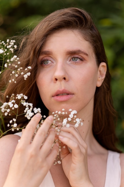 Free photo portrait of young woman posing confidently outdoors with flowers