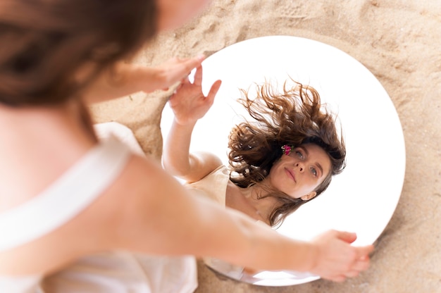 Free photo portrait of young woman posing confidently outdoors with a round mirror