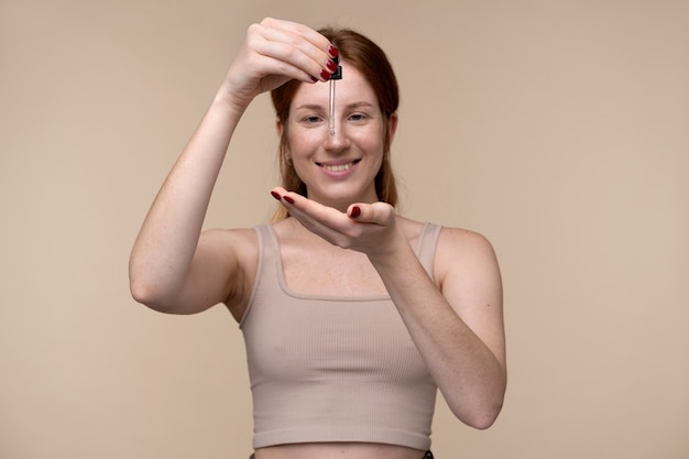 Free photo portrait of a young woman pouring serum on her hand