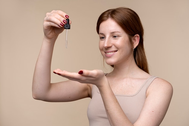 Free photo portrait of a young woman pouring serum on her hand