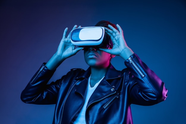 Portrait of young woman's playing in VR-glasses in neon light on blue