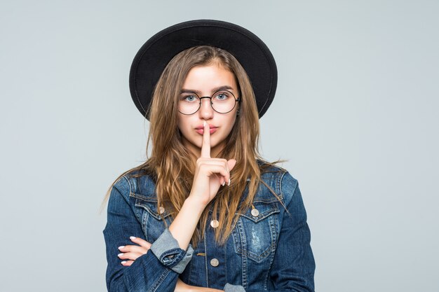 Portrait young woman showing silence gesture over gray background