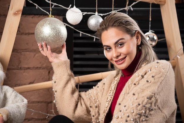 Portrait of young woman sitting on floor and holding a Christmas ball .High quality photo