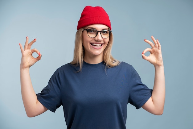 Free Photo portrait of a young woman smiling and showing the okay sign