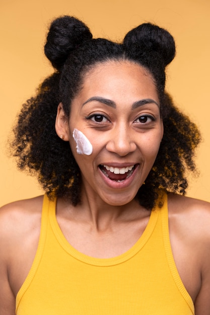 Portrait of a young woman smiling and wearing moisturizer on her face