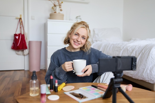 Free photo portrait of young woman social media influencer blogger sitting in front of camera with cup of tea