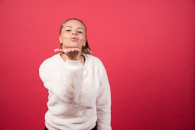 Portrait of a young woman standing and blowing an air kiss