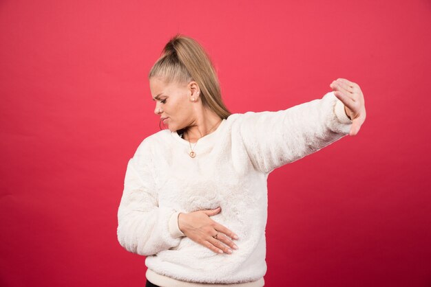 Portrait of a young woman standing and posing on a red wall