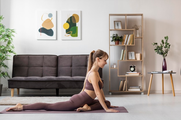 Portrait young woman stretching at home on mat