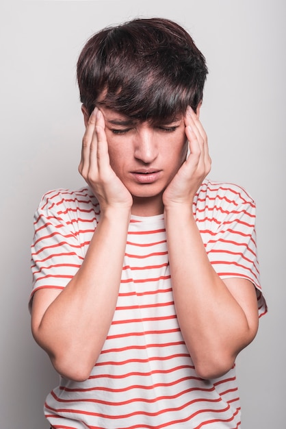 Portrait of young woman suffering from headache against white background