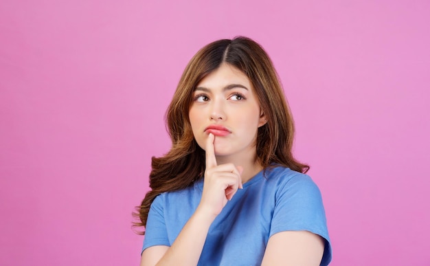 Portrait of young woman wearing casual tshirt thinking and imagination isolated over pink background