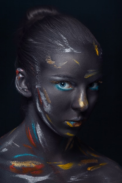 Free photo portrait of a young woman who is posing covered with  black paint