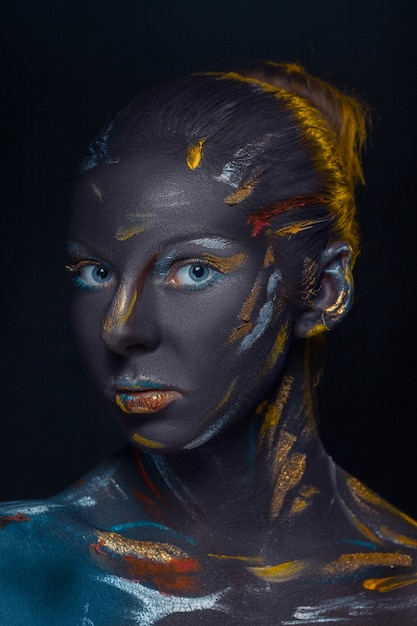 Free photo portrait of a young woman who is posing covered with  black paint