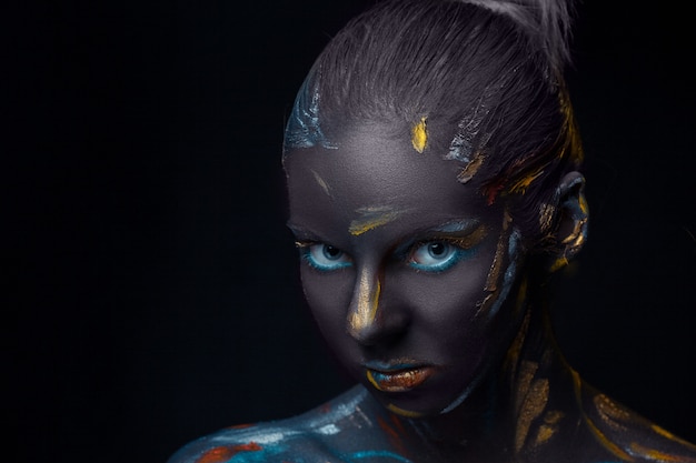 Portrait of a young woman who is posing covered with  black paint