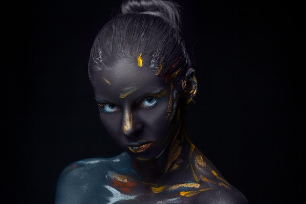 Portrait of a young woman who is posing covered with  black paint