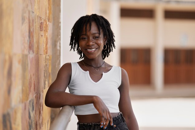 Portrait of young woman with afro dreadlocks posing outside