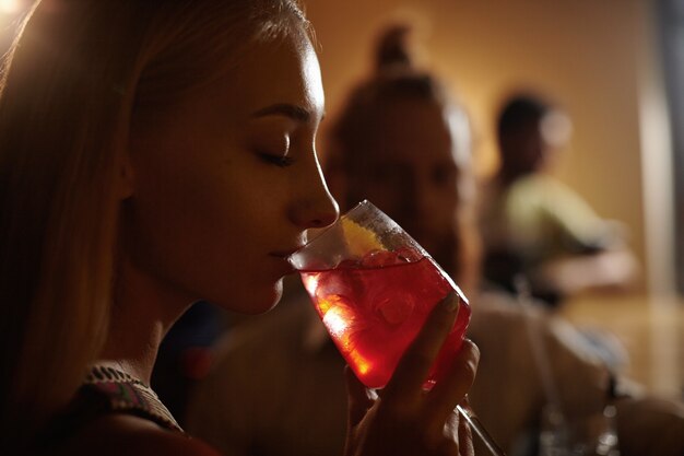 Portrait of young woman with blond hair holding cocktail