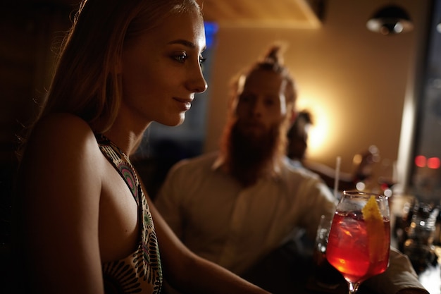 Free photo portrait of young woman with blond hair holding cocktail