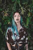 Free photo portrait of a young woman with dyed hair standing in front of plant