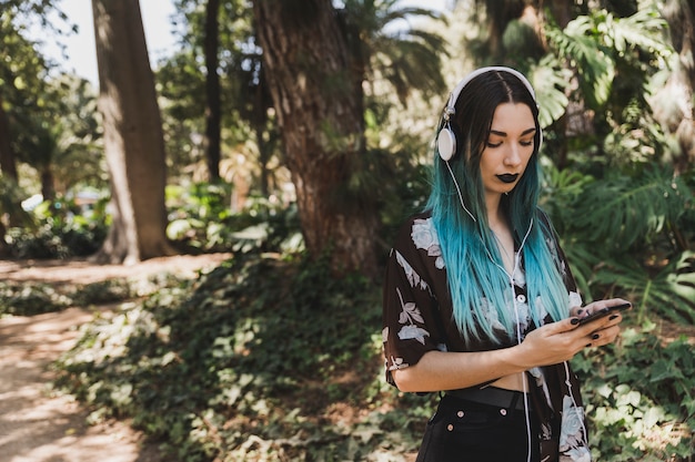 Free photo portrait of young woman with headphone on her head browsing cell phone