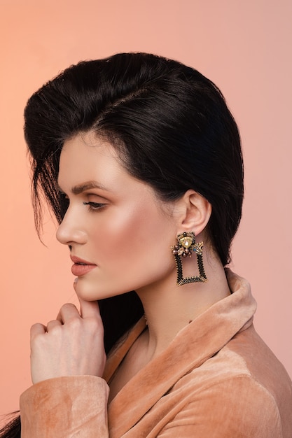 Free photo portrait of young woman with healthy skin and black square earrings isolated on pink wall