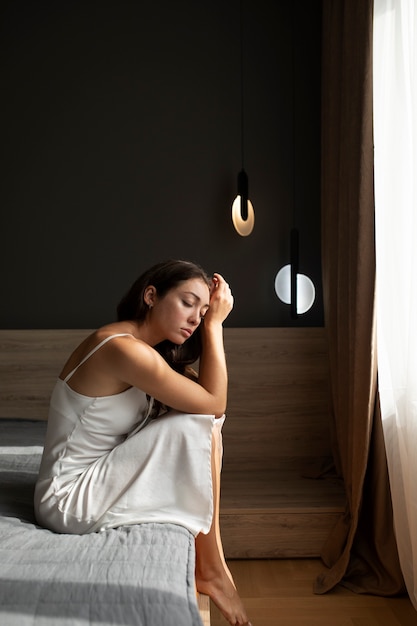 Portrait of young woman with low self-esteem sitting in bed at home