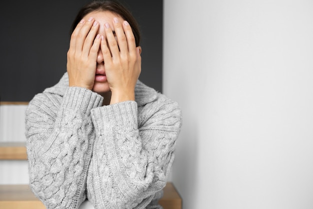 Free photo portrait of young woman with low self-esteem sitting on stairs at home