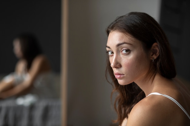 Portrait of young woman with low self-esteem with mirror