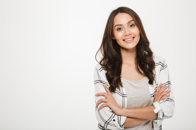 Portrait of young woman with magnificent smile standing with arms folded isolated, over white