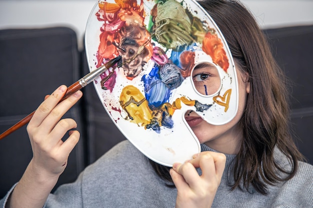 Free photo portrait of a young woman with a palette of paints