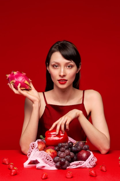 Portrait of young woman with selection of red fruits and vegetables in mesh bag