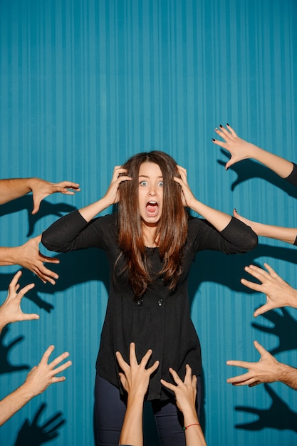 Free Photo portrait of young woman with shocked facial expression and many people's hands