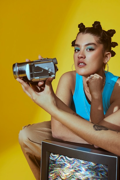 Portrait of young women in 2000s fashion style posing with tv and camera