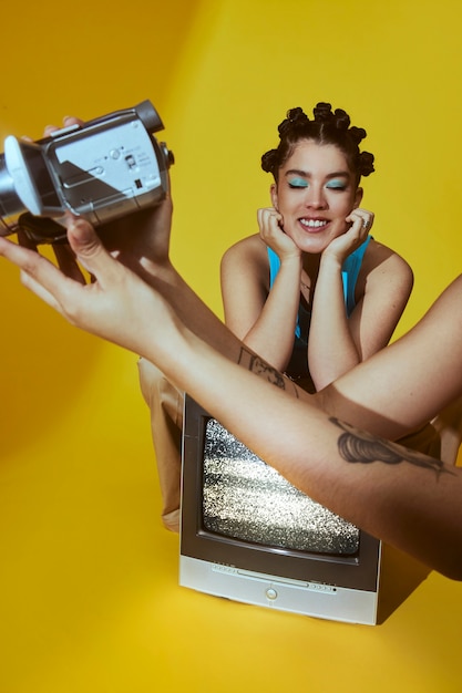 Free Photo portrait of young women in 2000s fashion style posing with tv and camera