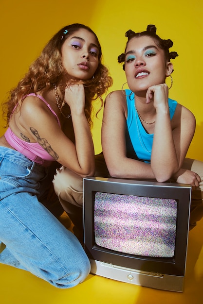 Portrait of young women in 2000s fashion style posing with tv