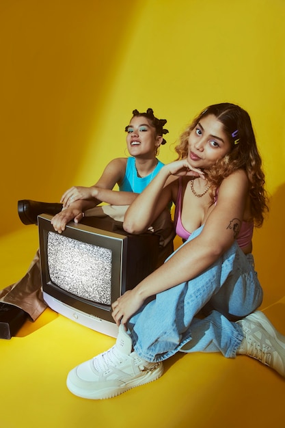 Portrait of young women in 2000s fashion style posing with tv