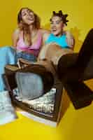 Free photo portrait of young women in 2000s fashion style posing with tv